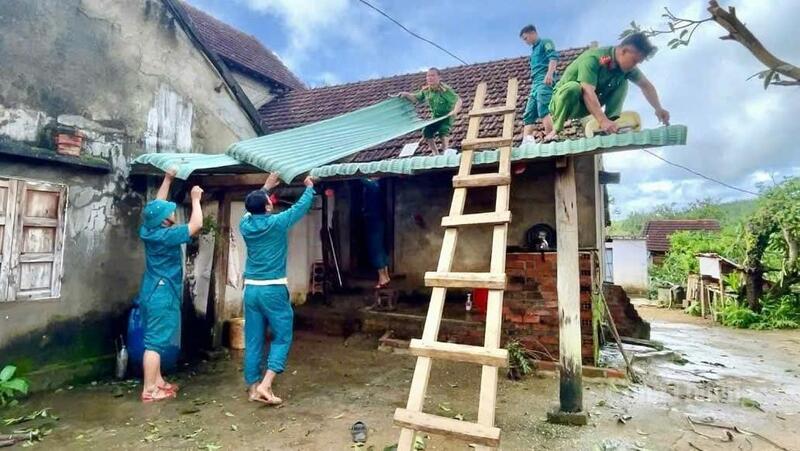 Lực lượng chức năng hỗ trợ người dân lợp lại mái nhà.