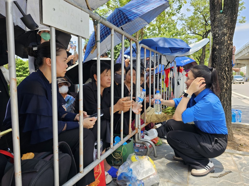 Người dân bên ngoài Nghĩa trang Mai Dịch nhận nước uống miễn phí từ thanh niên tình nguyện. Ảnh: Quân Thủy