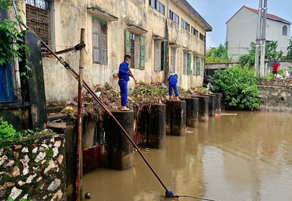 Công nhân vớt rác tạo dòng chảy tiêu thoát nước chống úng ngập tại Trạm bơm An Vọng (huyện Chương Mỹ).