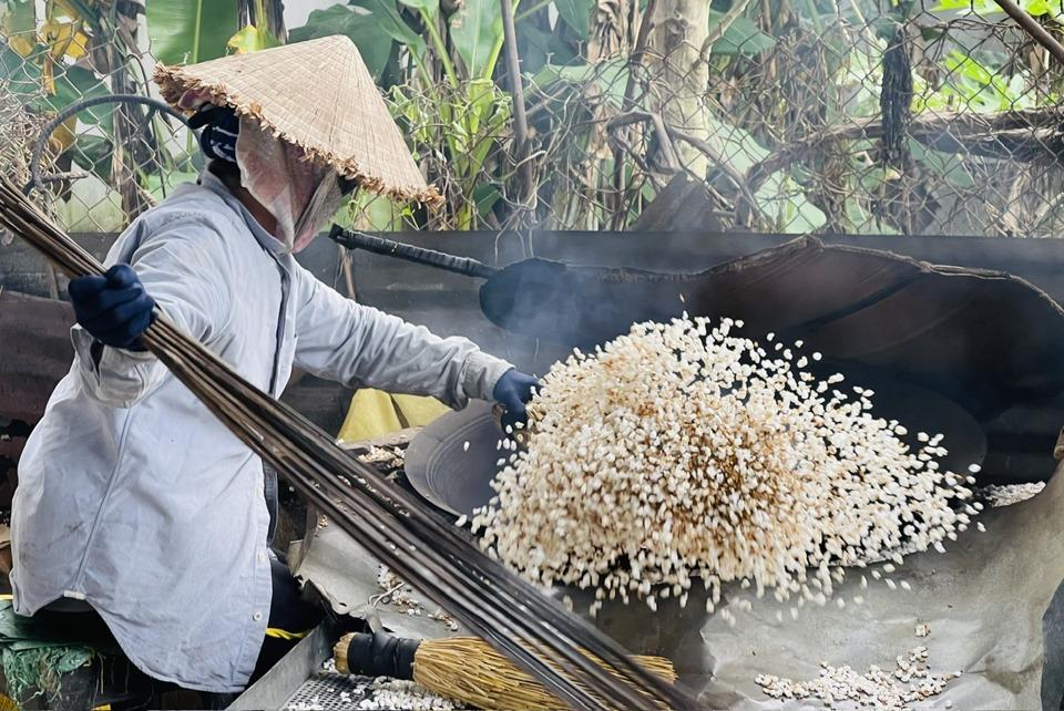 Nếp được rang trên bếp củi cho bong lớp vỏ trấu, lộ ra bỏng nếp trắng ngần.