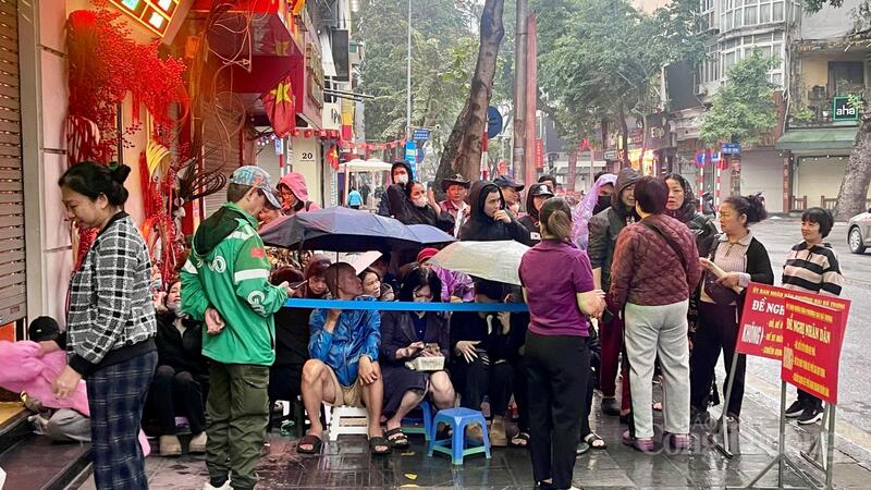 Dòng người mặc áo mưa, che ô kiên nhẫn xếp hàng dài trên phố Trần Nhân Tông.